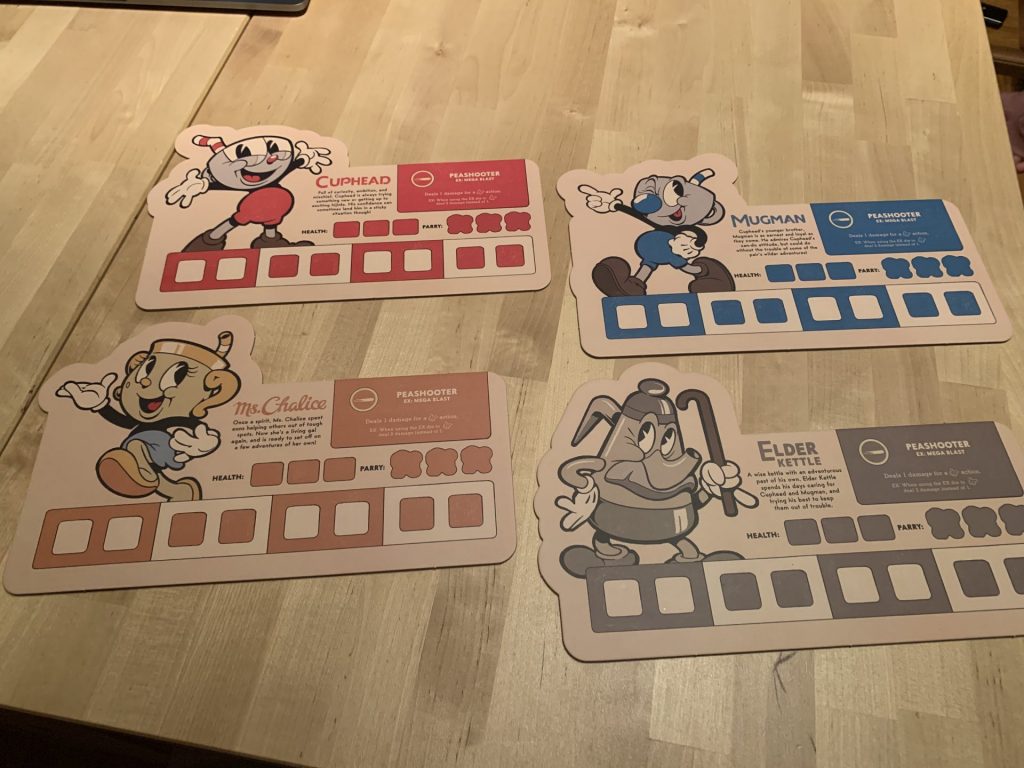 The four player boards, each showing one of the Cuphead characters.