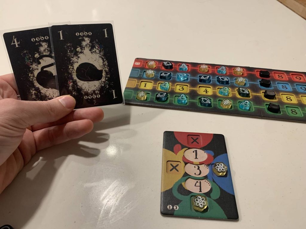 The player is holding a 1 and a 4. Their player board only has tokens on green and blue. There are tokens on every number except for the yellow 1, 3, and 4.