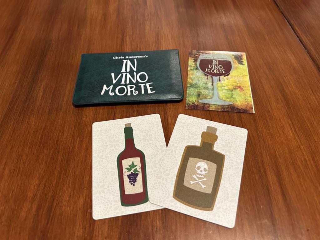 The wallet and instructions for In Vino Morte above one of each kind of card, the wine and the poison.