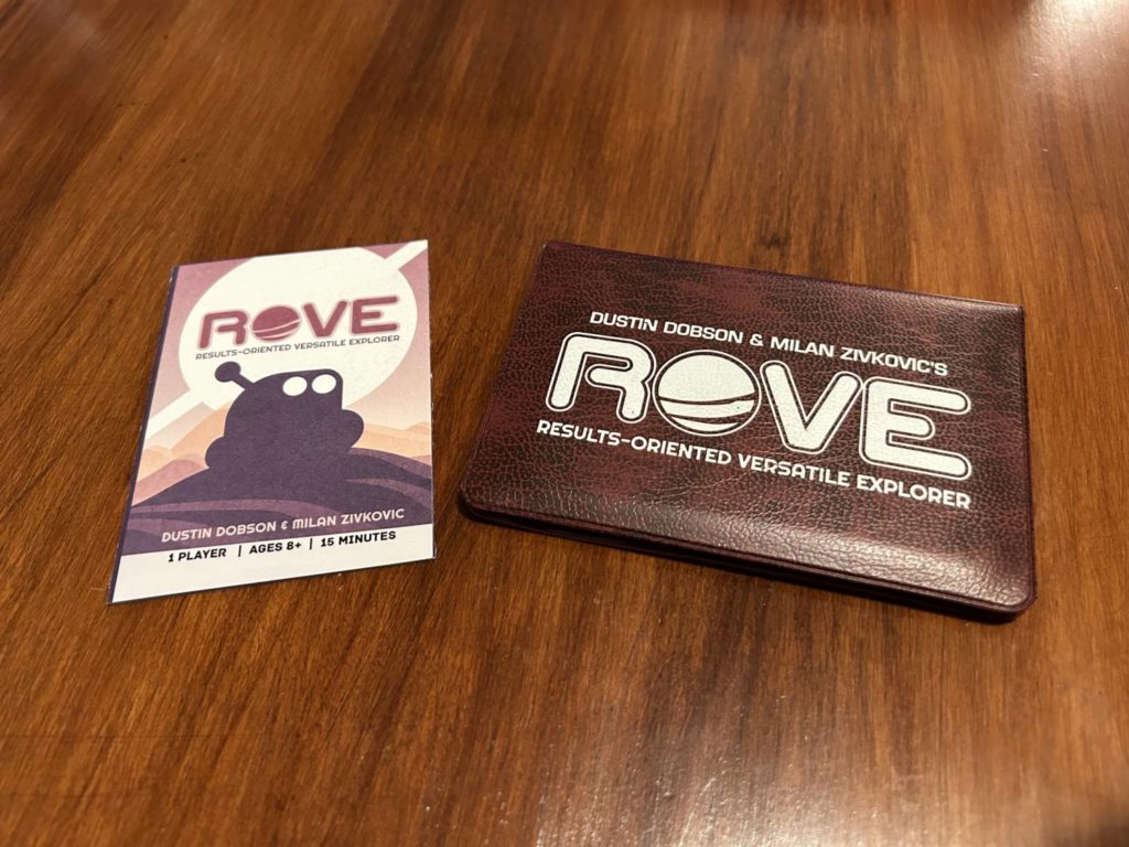 The ROVE instruction manual, which features the silhouette of the adorable titular robot, next to the card wallet.