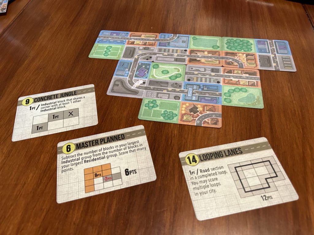 A tableau mid-game, three challenge cards laid out beside it.
