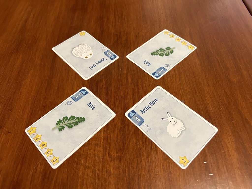 A trick with four cards in the Arctic suit: An owl, a rabbit, and two kale.