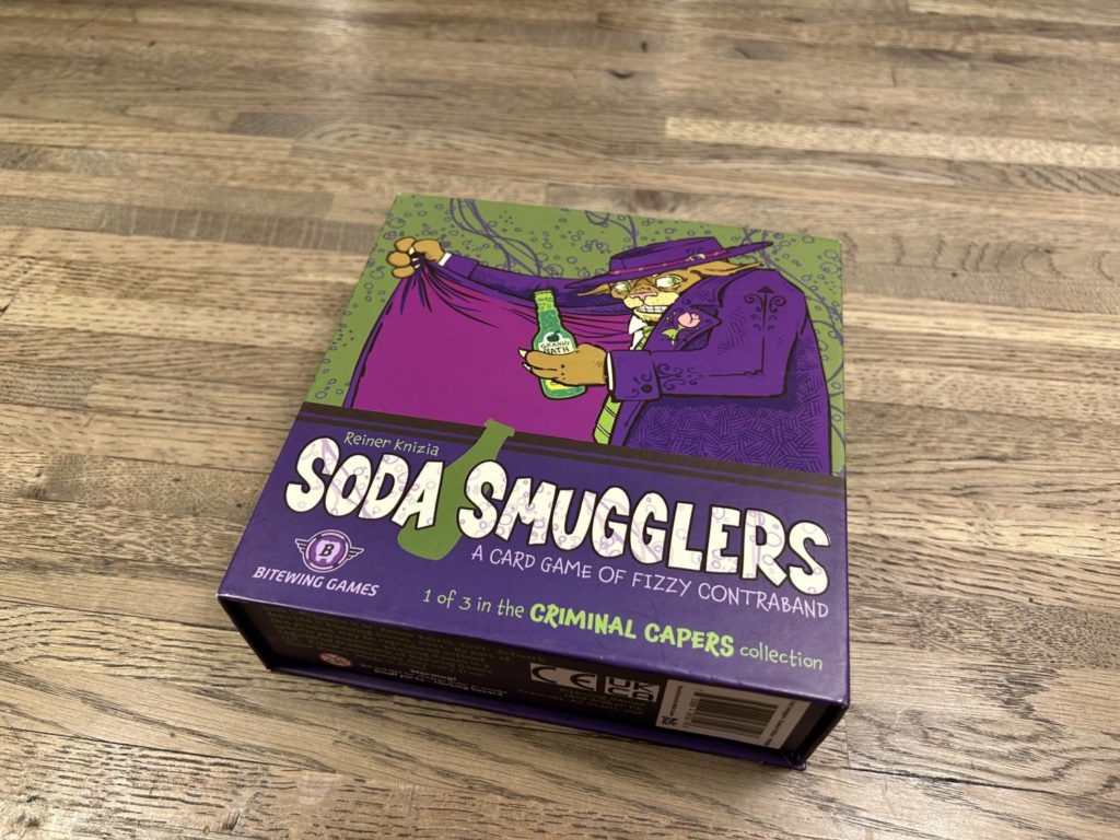 The Soda Smugglers box, which uses a fun color palette of dark purples and light greens.