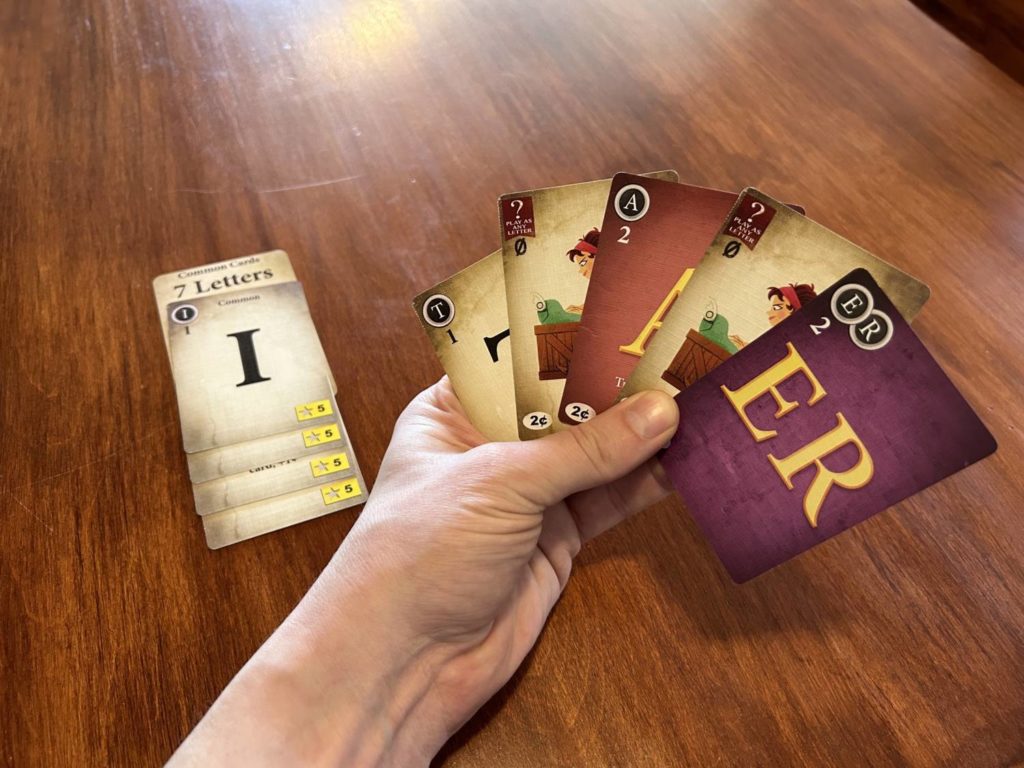 A hand of cards and the "I" common card in the background.