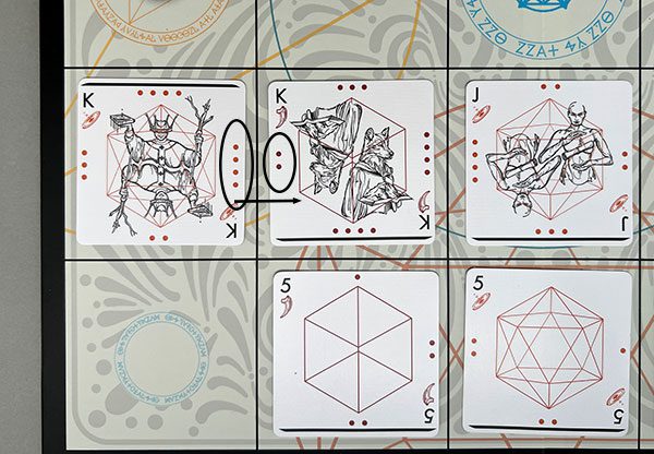 The North player's King of Souls (ownership denoted by the solid line pointing north) is set to attack the South player's King of Claws. The dots along each adjoining edge shows who will win--in this case, the King of Souls will capture South's King of Claws and move into its square on the board.