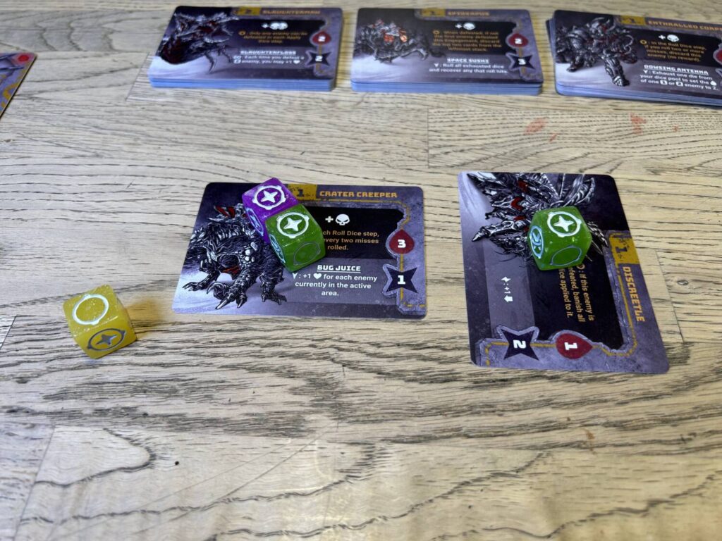 Two alien cards, with hits assigned. One card has been rotated sideways to indicate that it has been defeated.