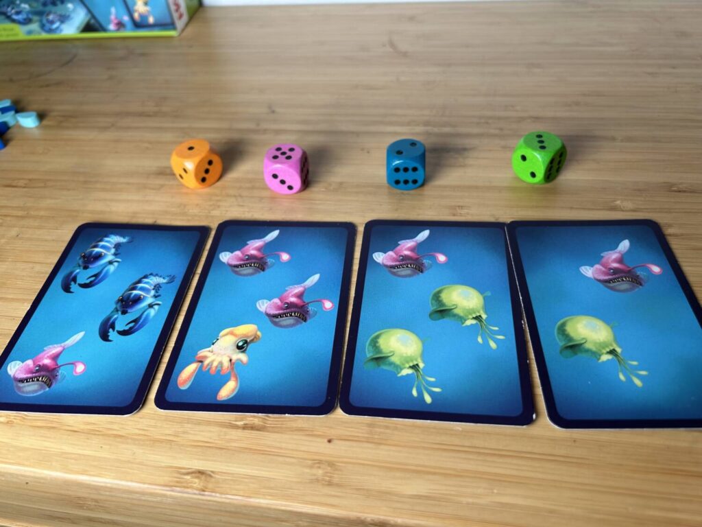 A series of four cards, next to dice which accurately reflect the number of each type of fish present.