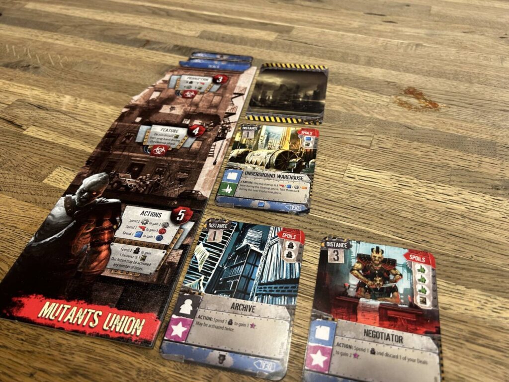 A player board, which is tall and narrow, with four buildings played in three rows next to it.