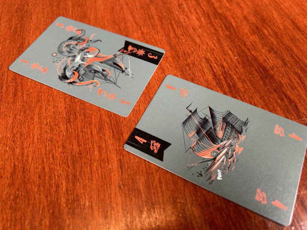 A pair of cards, one with the cannon icon and the other with a helm and a kraken tentacle.