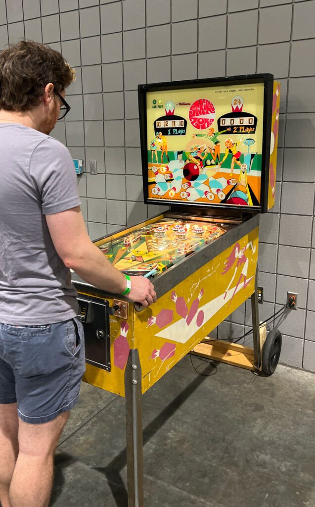 The vintage pinball machine, placed against the tiled wall that bounced all the sounds back into the wider area.