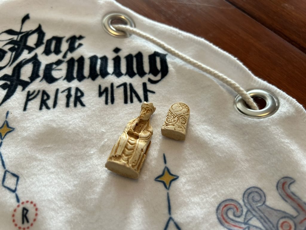 A closer photograph of the King and a Pawn. They are cast in off-white resin that looks like ivory, with details emphasized by yellowing.