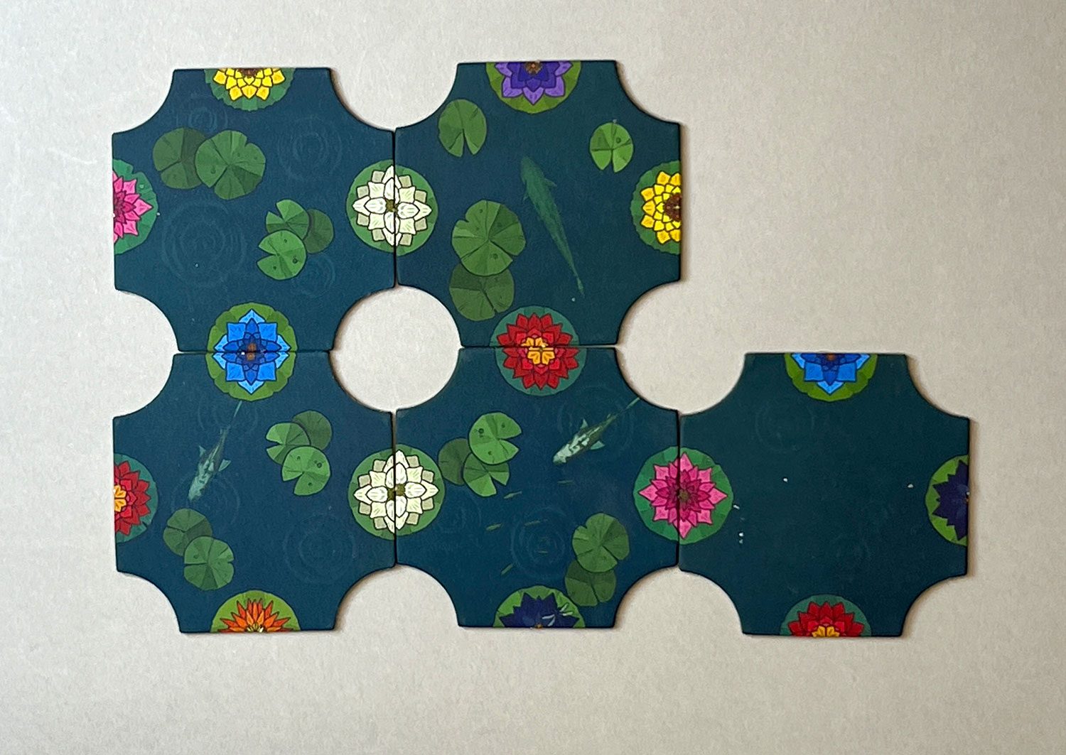 With four connecting tiles forming a circle in the center, you can now place a wooden marker. You can choose either a White lily marker, or a blue or a red with a yellow center lily token.