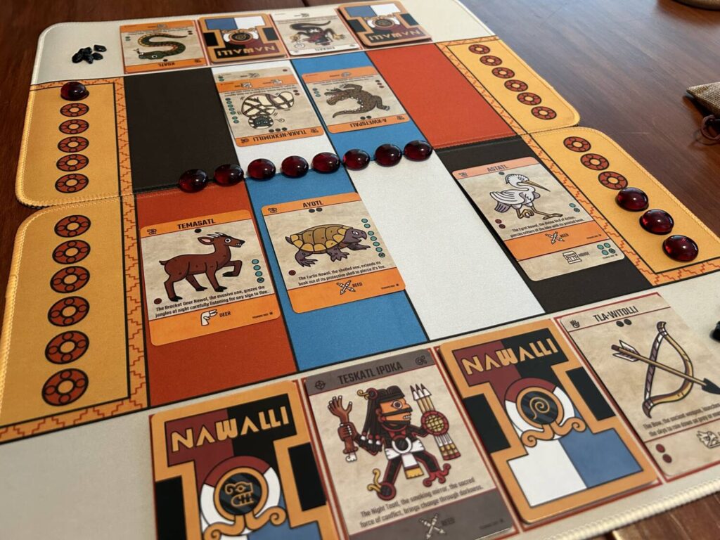 A game of Nawalli, with the two playmats. Cards are played across four lanes, each boldly colored. Below the lanes, each player has space for two draw piles, their Nawal, and a discard pile.