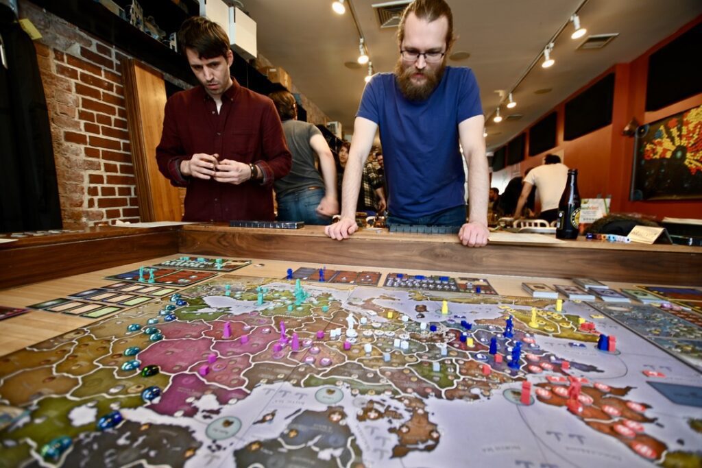 Two players survey the massive board for Eurpopa Universalis: The Price of Power. The map shows the entirety of the European Continent, from the Atlantic to Russia.