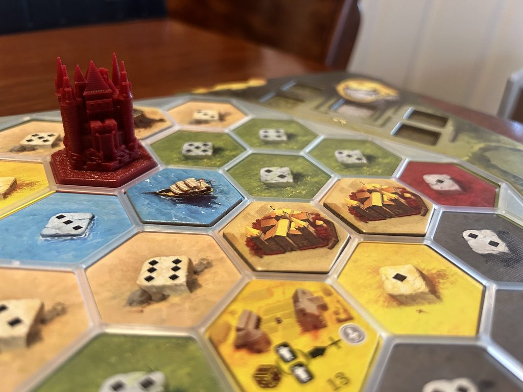 A close up photograph of one of the dual-layer player boards, with standard tiles and a 3D castle.