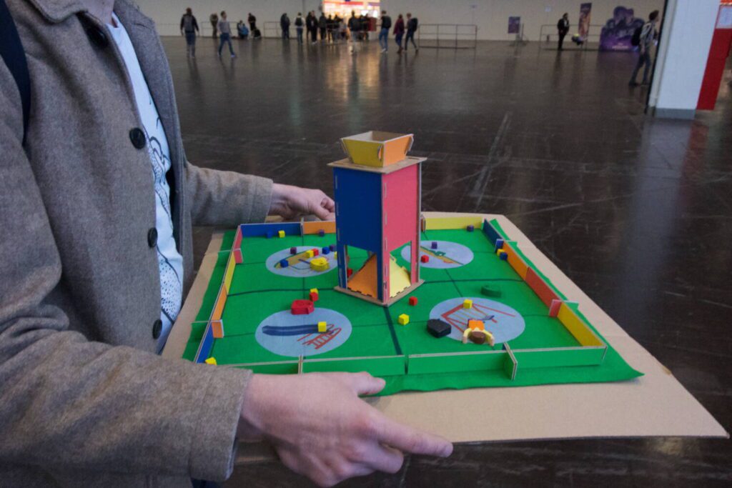 A close-up shot of the pigeon board game, with its colorful green mat and cube tower.