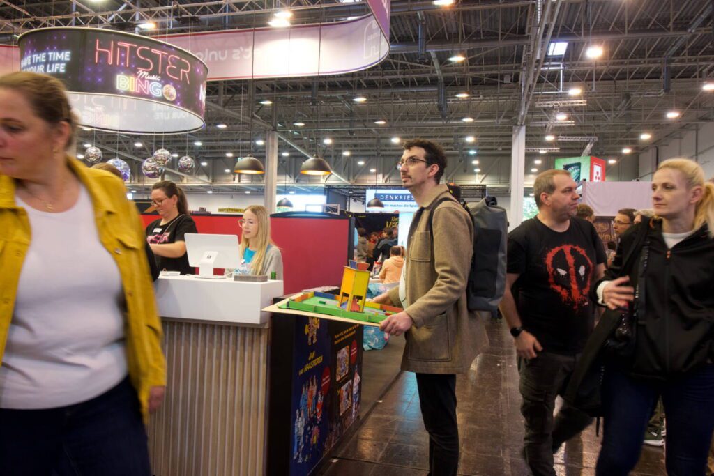 Jim Williams stands in the midst of a crowded convention hall, holding a large horizontal board.