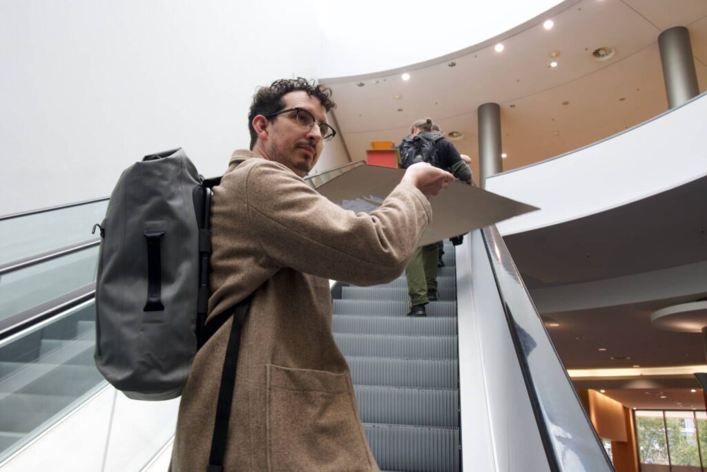 Jim riding an escalator, the pigeon game still in hand.