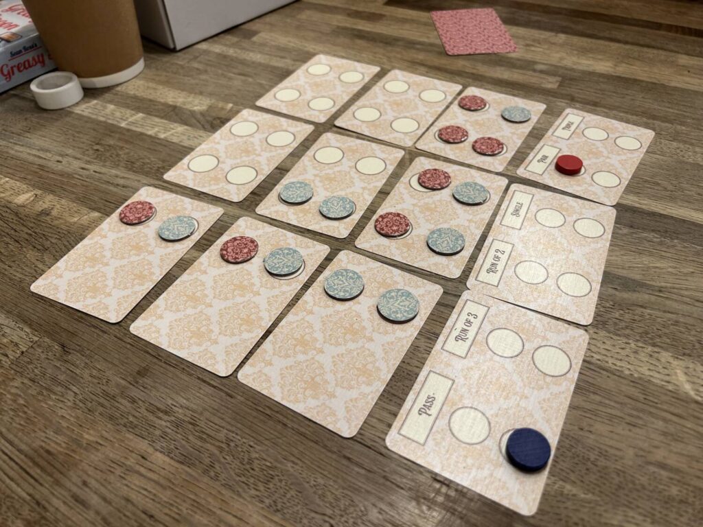 The Lepidoptery board is made up of 12 cards, laid out in a 4 x 3 grid. The game of Connect Four is played out across a 6 x 5 grid shown on those cards.