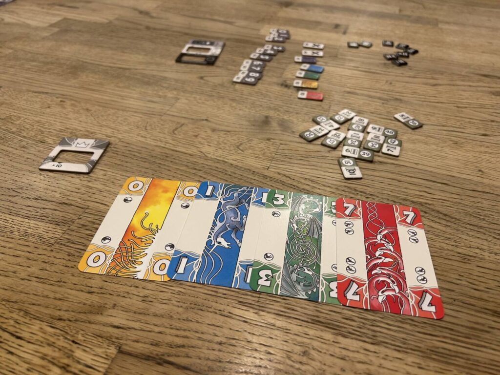 A row of cards from the deck, laid out on the table. The bid tokens can be seen strewn about the middle of the table.