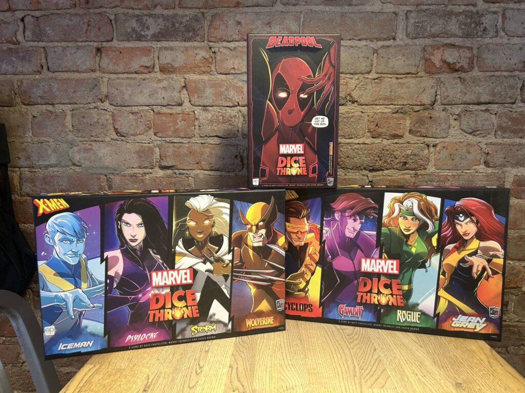 Three boxes, two full-sized and one smaller, containing all of the products in the Marvel Dice Throne: X-Men line