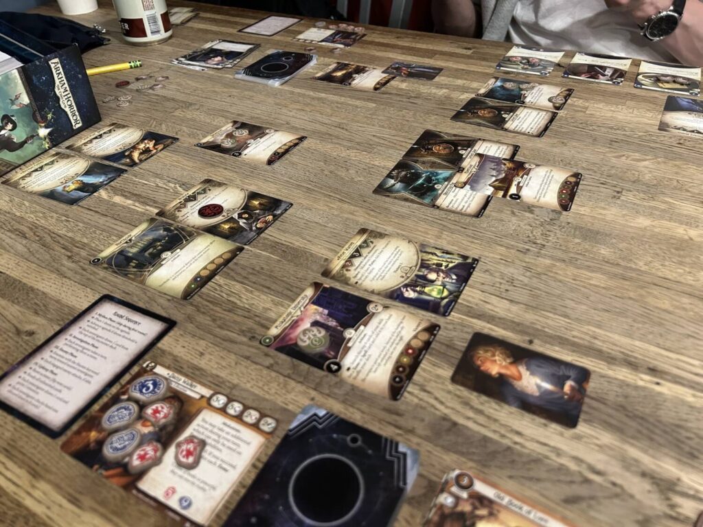 A large number of cards and tokens on a wooden table.