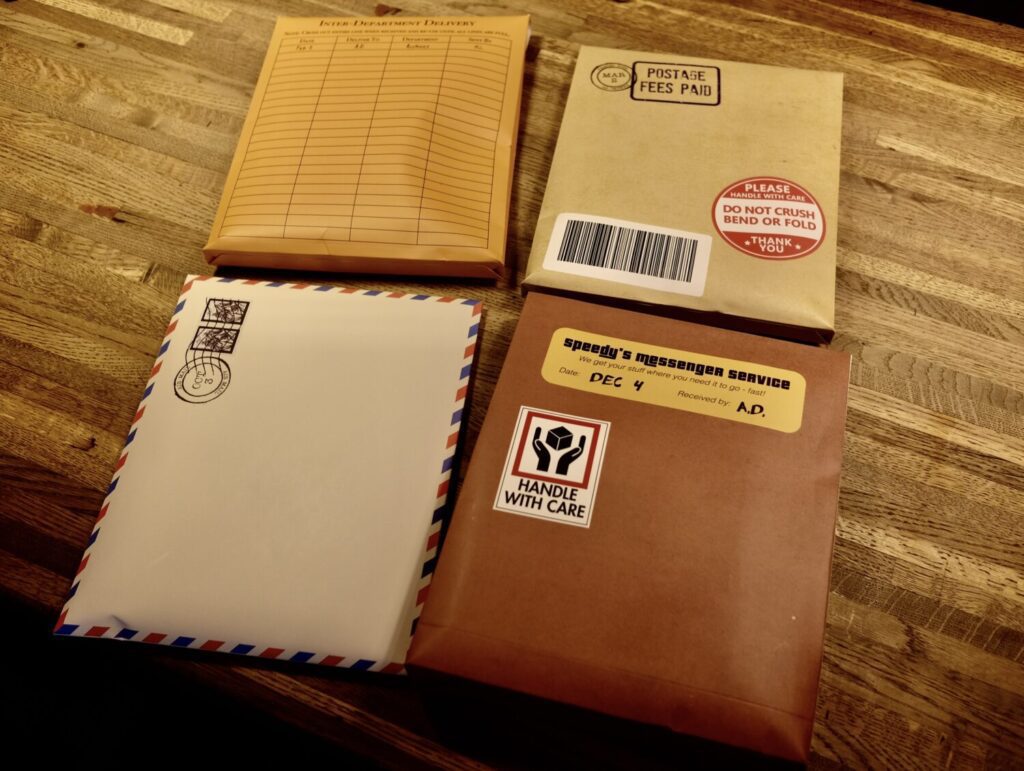 Four oversized envelopes, each containing a portion of the game.