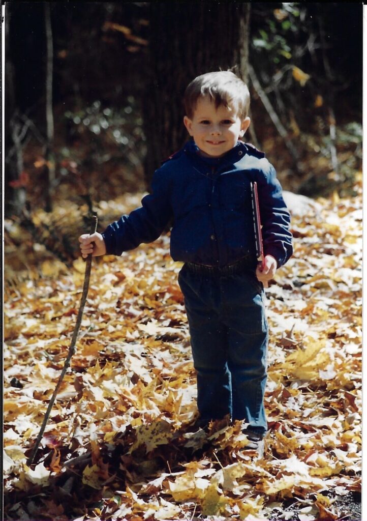 The author as a young man, surrounded by foliage in a New England forest.