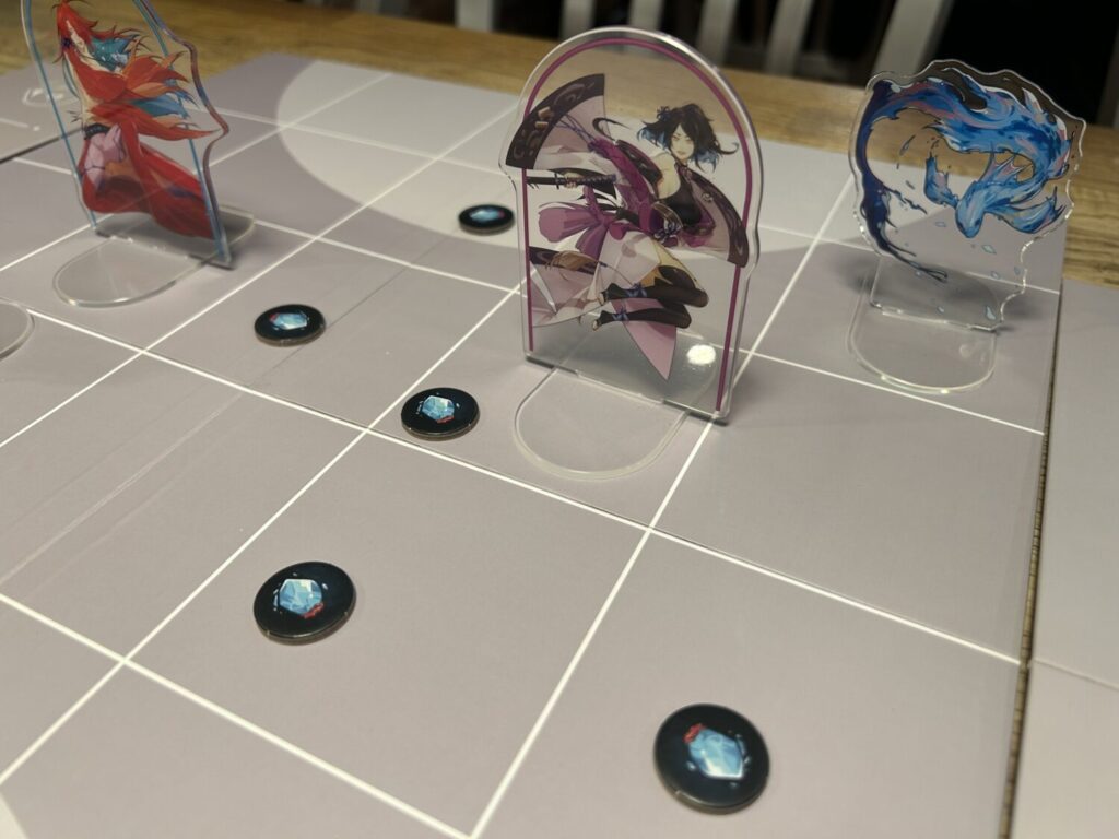 A series of clear acrylic standees on a grey, mostly plain board. Circular cardboard fish scale tokens are in some of the spaces.