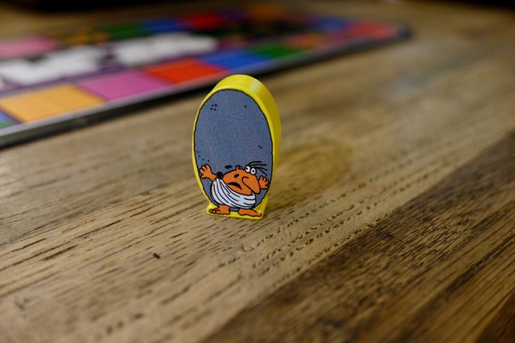 The character token for Sisyphus, a small orange man holding an enormous grey boulder, stands on the table.