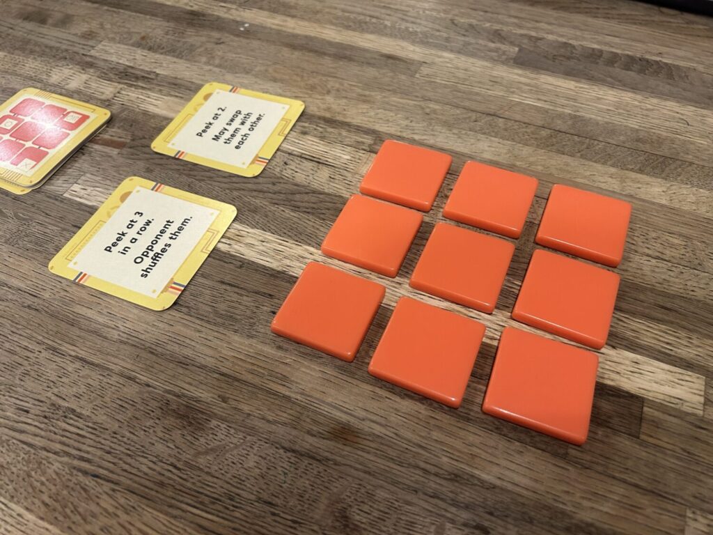 A game during setup, with nine tiles in a 3x3 square and two face-up cards off to the side.