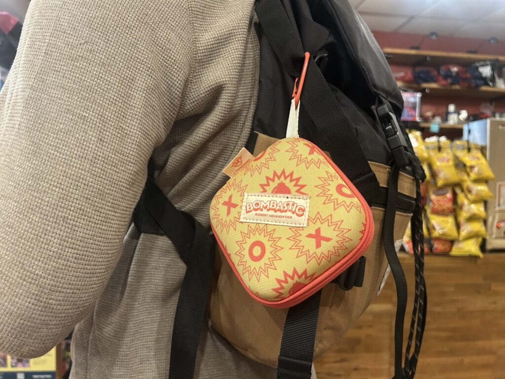 A bright yellow square case, clipped to a backpack. It feels like elementary school and camping trips.