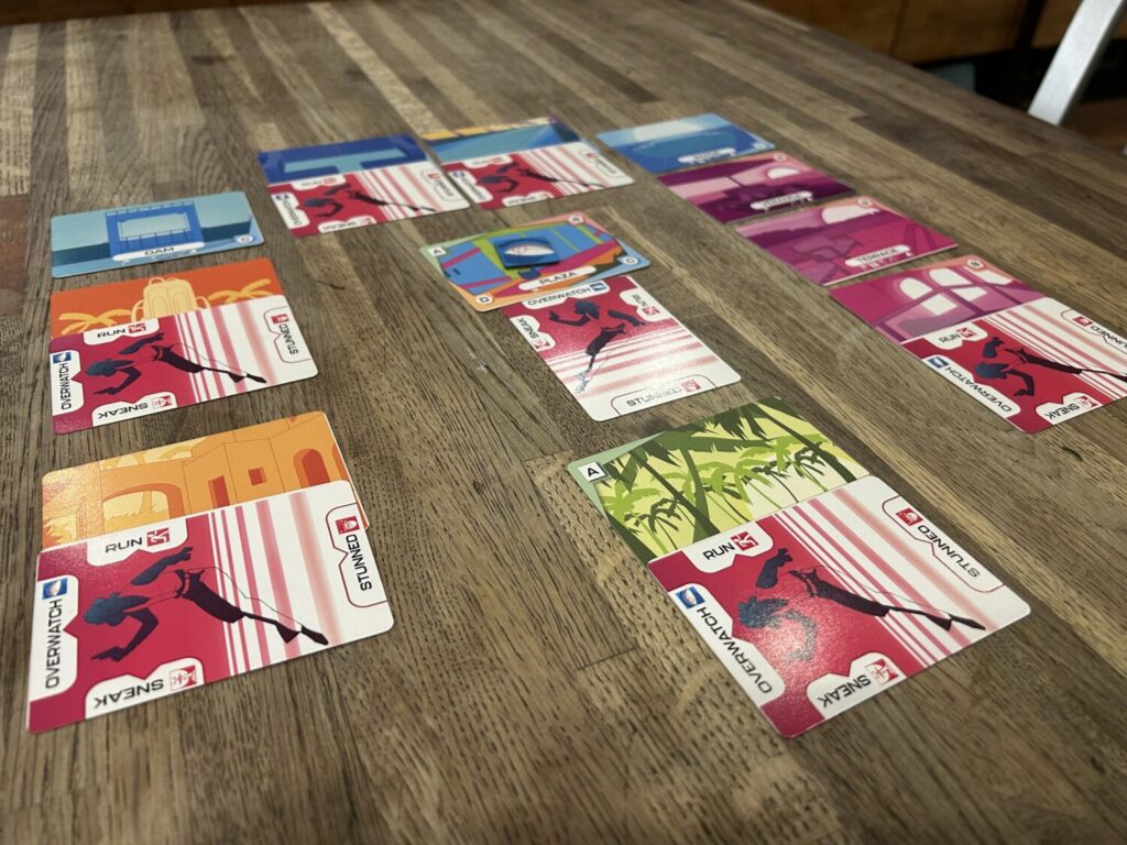 Location cards laid out on a wooden table. They are rendered in vaporwave neon colors.