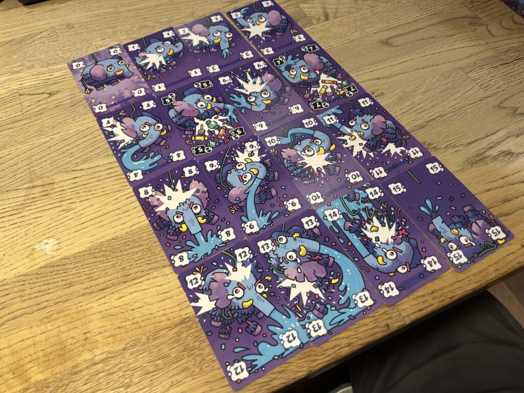 Sixteen cards in one suit are laid out on a wooden table in a 4x4 grid. They show the frankly horrifying experience of an elephant piñata as it gets the ever-loving shit kicked out of it by an unseen antagonist.