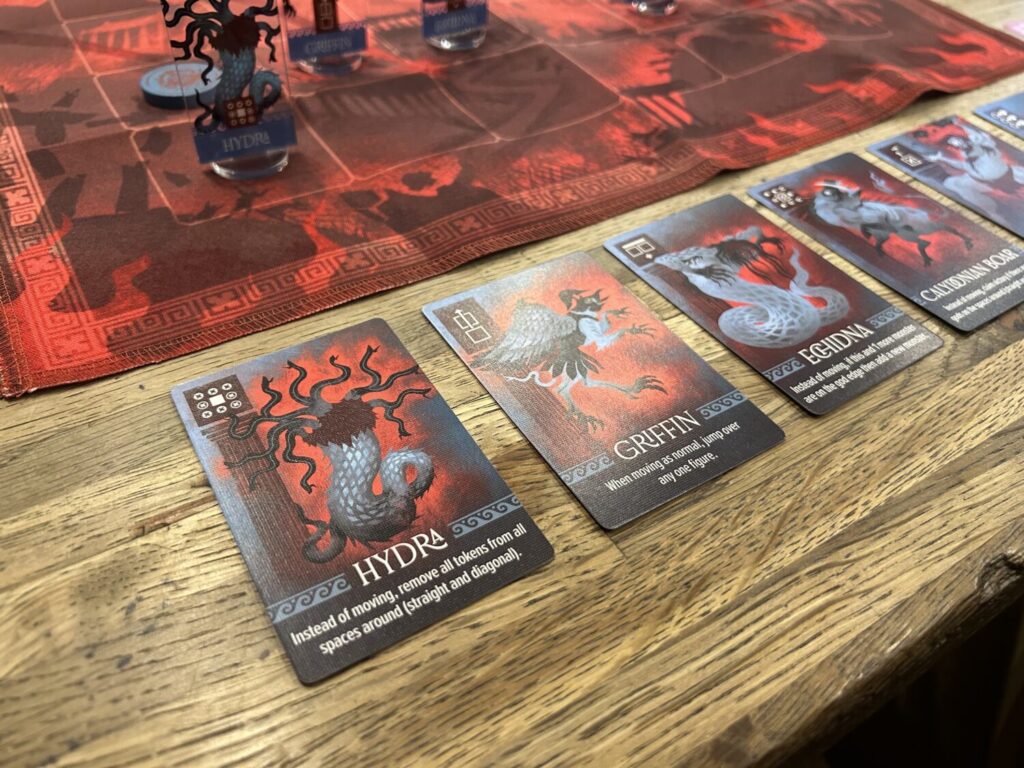 Several Monster cards on a wooden table, each with an illustration and a text explanation of their power.
