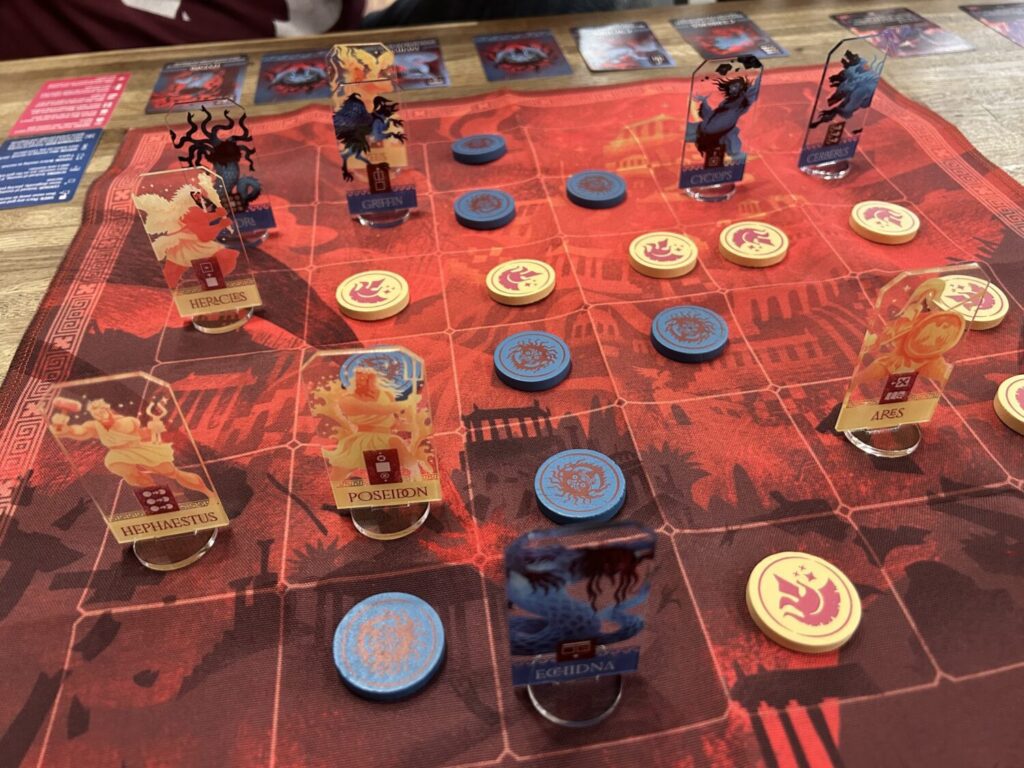 Another photo of the red cloth board, with acrylic standees and wooden tokens.