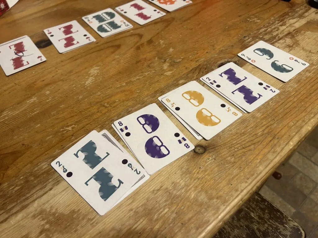 Five stacks of two cards each in a row on a wooden table.