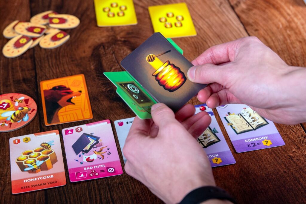 A pair of hands hold a small manila folder, into which a stack of cards have been placed facedown.