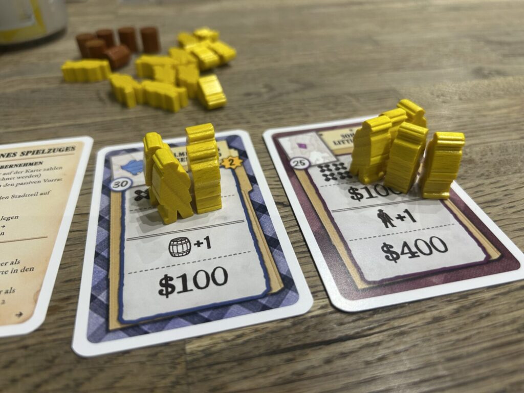 Several territory cards on a wooden table, each with a stack of meeples on it.
