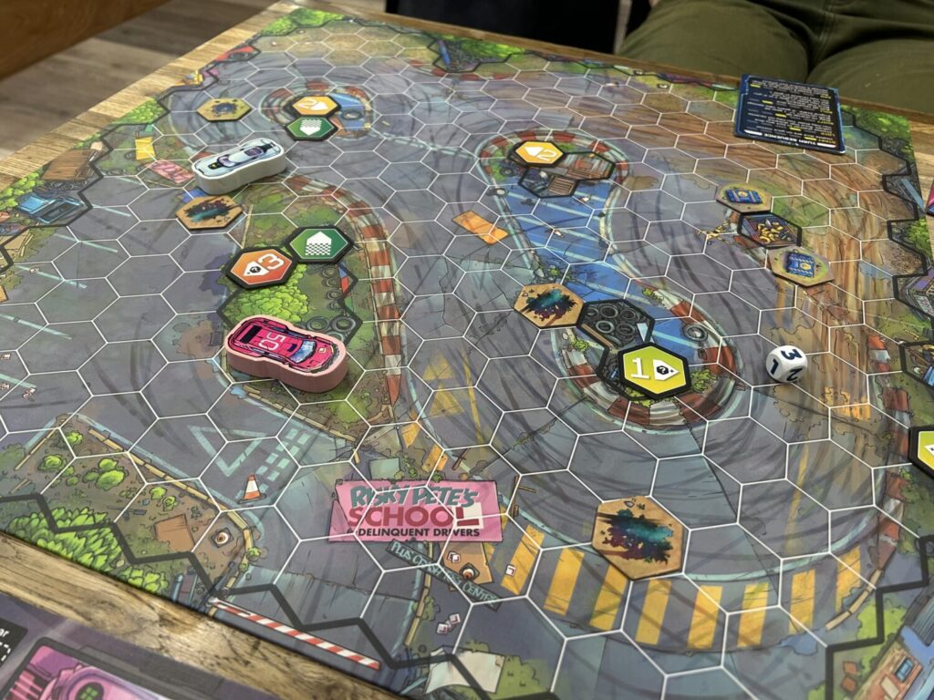 A wide shot of the board, with two thick wooden cars making their way around corners. The board is divided into a large number of hexagons.