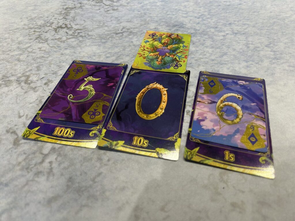 Another photo of the same tarot-sized cards, though this time the first one is covered with a five, the second is uncovered but has an Ace above it, and the last one is covered by a 6.