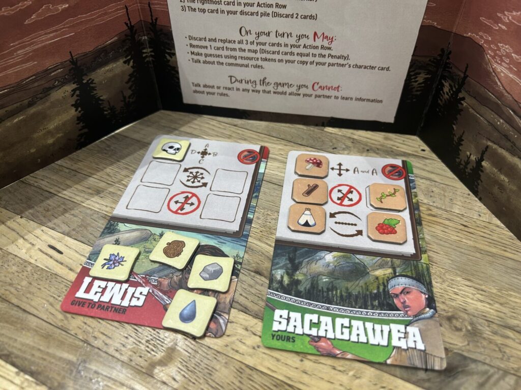 Two player cards sit behind a privacy screen. Each has three rows, corresponding to different rules that must be followed. The card to the right is filled with tokens.