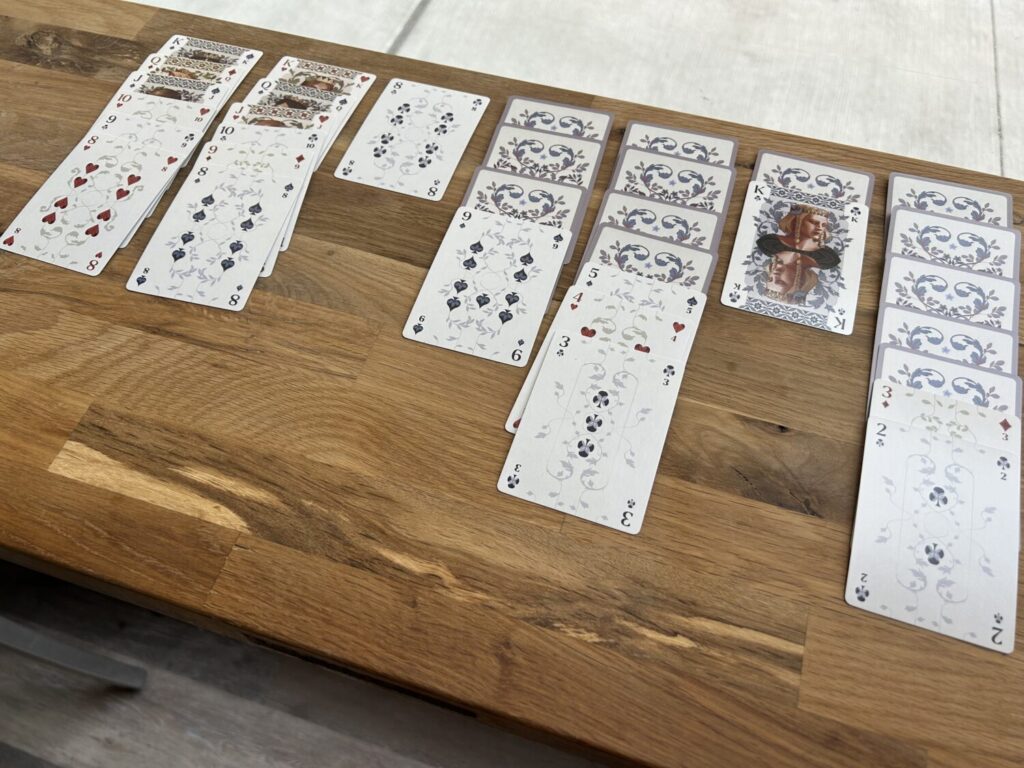 A game of solitaire set up on a wooden table.