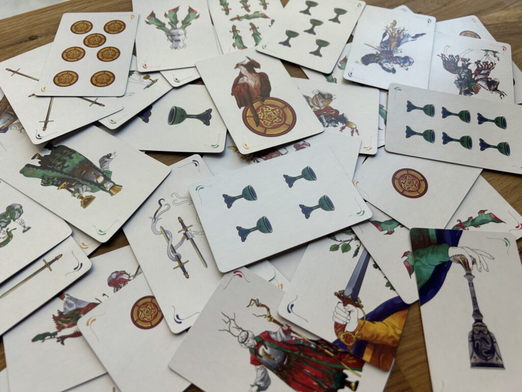 A mess of scopa cards, spread out on a wooden table.